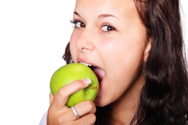 Woman taking bite out of a green apple Edmond Dentist