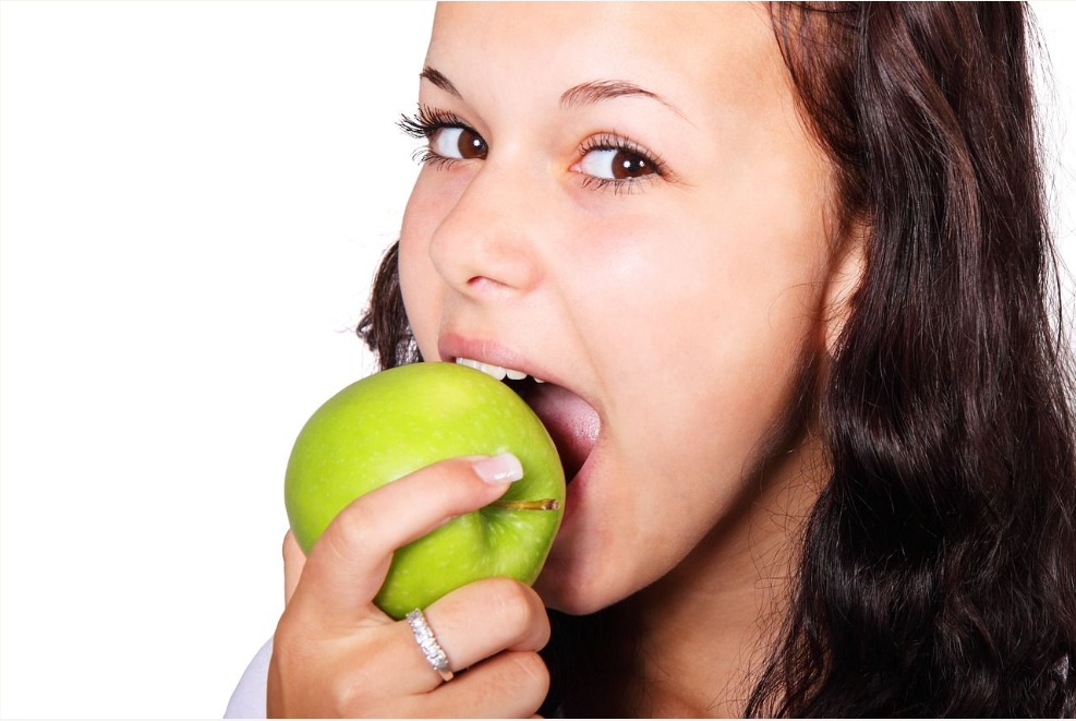 Woman taking bite out of a green apple Edmond Dentist
